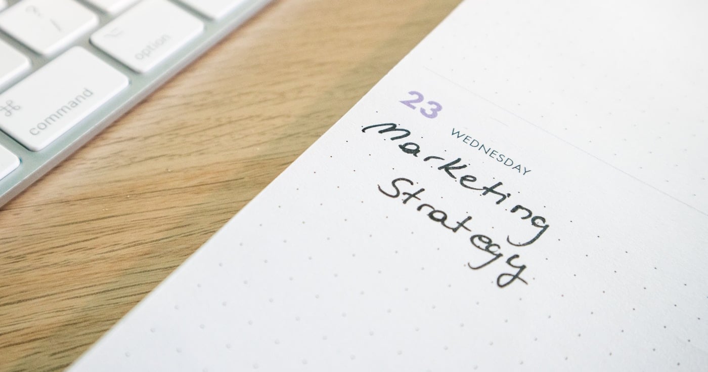 A planner with the words Marketing Strategy on a desk with a keyboard