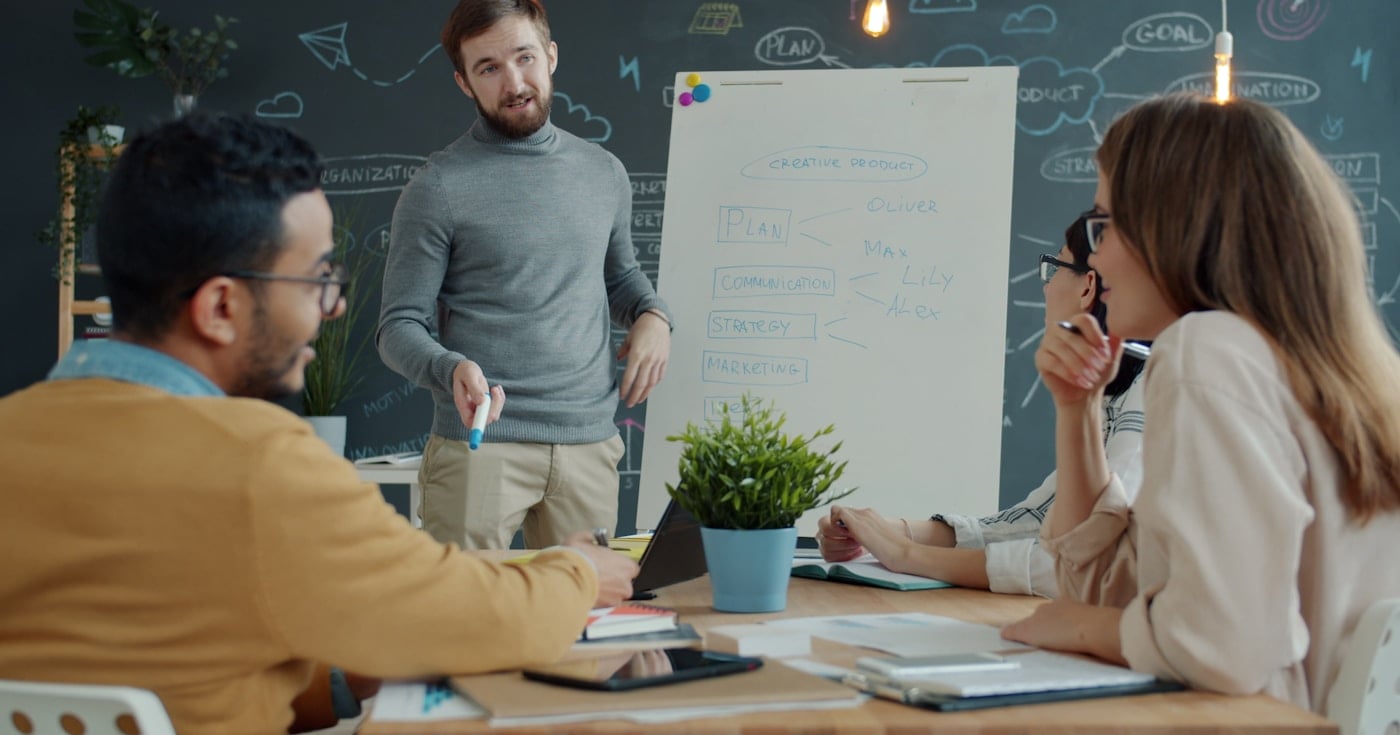 Marketing team discussing demand generation strategy at whiteboard