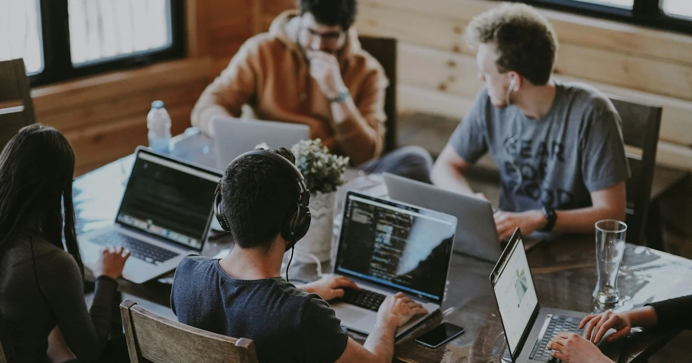 Team of marketers working on laptops around a shared table